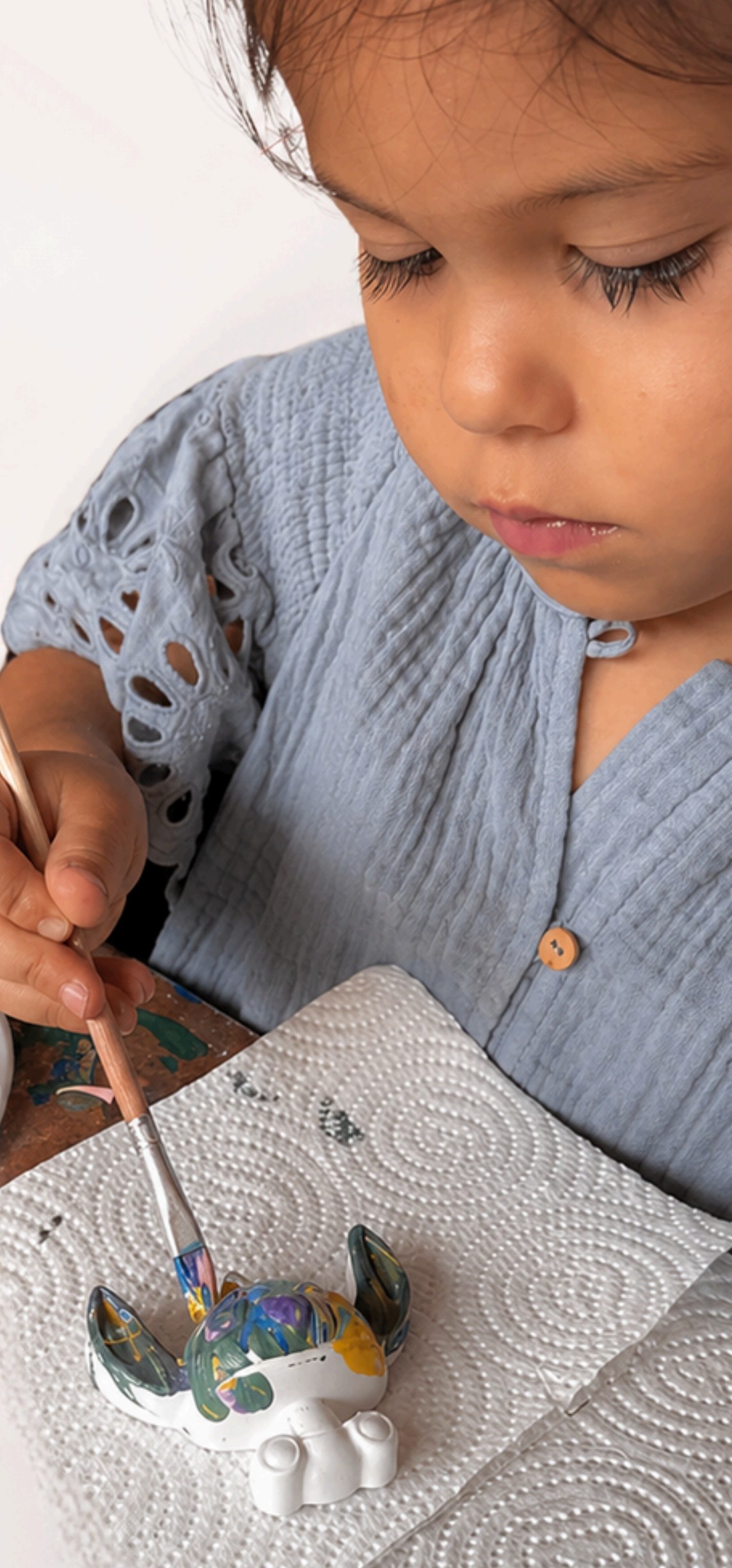 Niña concentrada pintando una figura artesanal de Mom&Co.